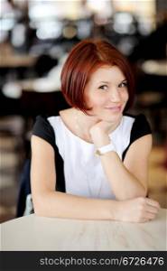Portrait of beautiful woman with red hair sitting at a table
