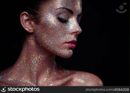 Portrait of beautiful woman with sparkles on her face. Girl with art make up in color light. Fashion model with colorful make-up
