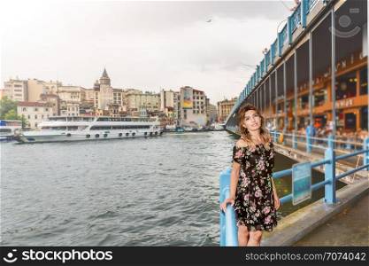 Portrait of beautiful woman with view of Galata bridge,New Mosque and Eminonu Town in Istanbul,Turkey. Beautiful woman travels with ferry between Asia and Europe