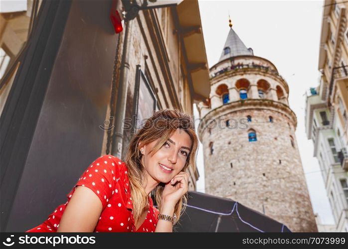 Portrait of beautiful woman with view of Galata tower in Beyoglu,Istanbul,Turkey. Beautiful woman in red dress sits on a ferry Istanbul on background.