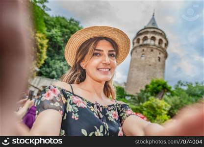 Portrait of beautiful woman with view of Galata tower in Beyoglu,Istanbul,Turkey. Beautiful woman in red dress sits on a ferry Istanbul on background.