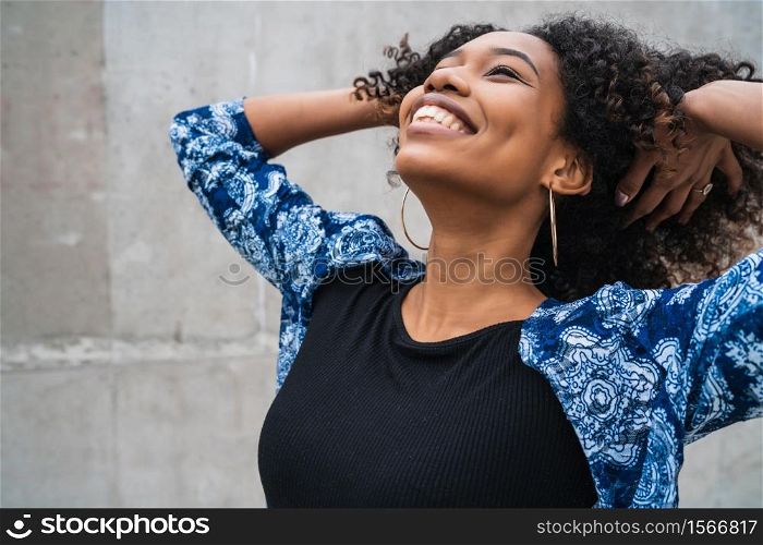 Portrait of beautiful young afro-american confident woman happy and excited against grey wall. Success concept.