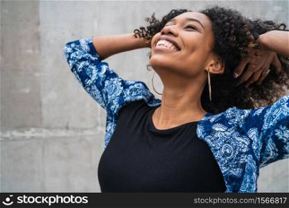 Portrait of beautiful young afro-american confident woman happy and excited against grey wall. Success concept.