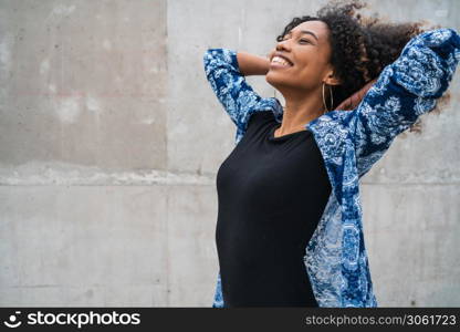 Portrait of beautiful young afro-american confident woman happy and excited against grey wall. Success concept.