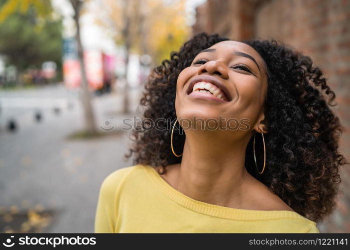 Portrait of beautiful young afro-american confident woman laughing in the street. Outdoors.