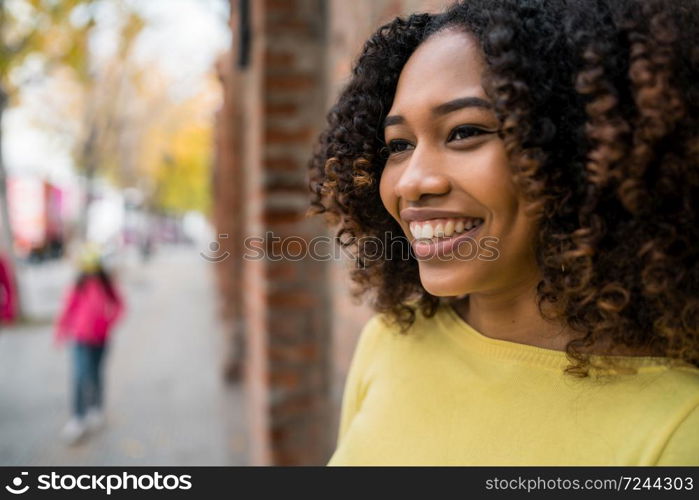 Portrait of beautiful young afro-american woman with curly hair standing outdoors in the street.