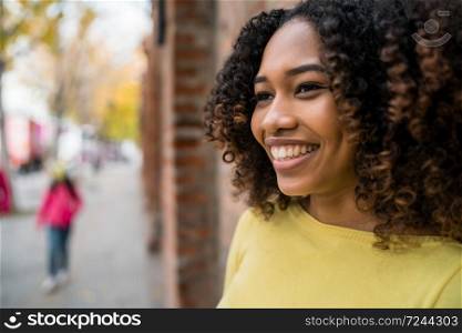 Portrait of beautiful young afro-american woman with curly hair standing outdoors in the street.