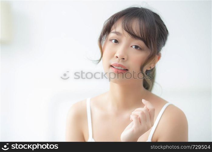 Portrait of beautiful young asian woman smile while wake up healthy and wellness with sunrise at morning in the bedroom, asia girl skin care with happy with fresh, lifestyle and relax concept.