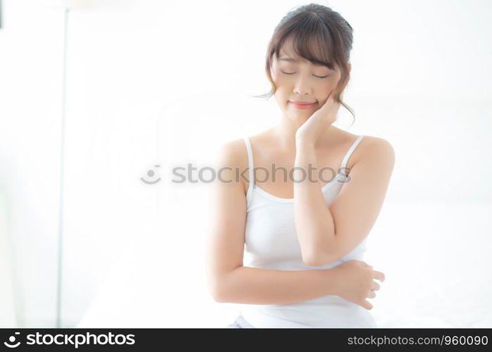 Portrait of beautiful young asian woman smile while wake up healthy and wellness with sunrise at morning in the bedroom, asia girl skin care with happy with fresh, lifestyle and relax concept.