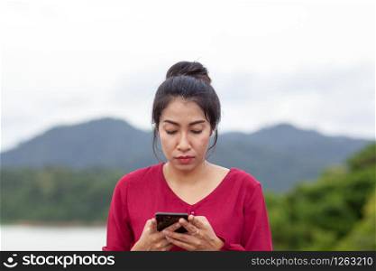 Portrait of beautiful young asian woman with Carmen red dress reading messages on her smartphone