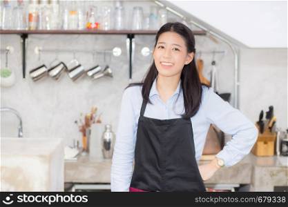 Portrait of beautiful young barista, asian woman is a employee standing in counter coffee shop, service concept.
