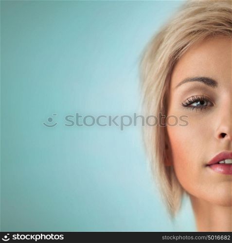Portrait of beautiful young blond woman with clean face on blue background
