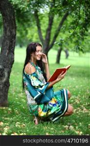 Portrait of beautiful young blonde girl reading a book in the park