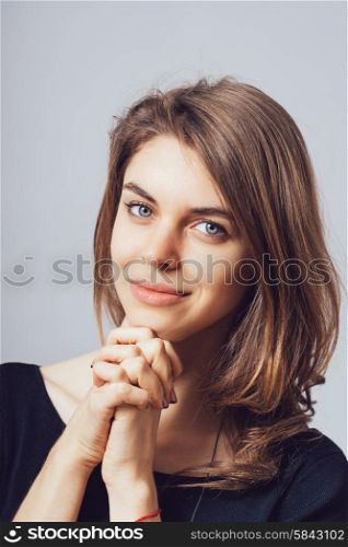 portrait of beautiful young brunette girl holding hand on chin isolated on gray background