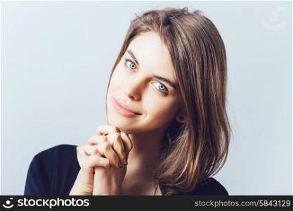 portrait of beautiful young brunette girl holding hand on chin isolated on gray background