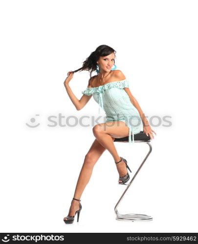 portrait of beautiful young brunette woman in stylish dress and black shoes sitting on bar chair. Nice woman in dress sitting in chair