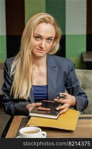 Portrait of beautiful young business woman holding office supplies sitting in office.. Portrait of business woman in office.