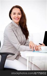 Portrait of beautiful young business woman sitting at desk at office