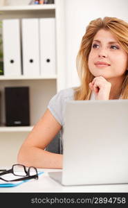 Portrait of beautiful young business woman sitting at desk in the office