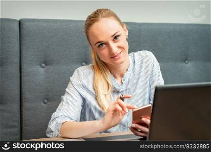 Portrait of beautiful young caucasian businesswoman with smartphone working in office looking and smiling at camera. Businesswoman with smartphone working in office