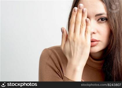 Portrait of beautiful young caucasian woman covering her half face with her hand on white background. Woman covering half face with hand