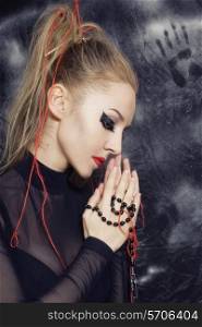 Portrait of beautiful young Caucasian woman with makeup in Gothic style, and his hands clasped in prayer