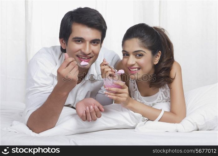 Portrait of beautiful young couple eating ice-cream in bed