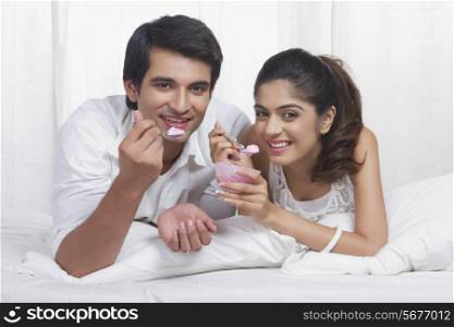 Portrait of beautiful young couple eating ice-cream in bed
