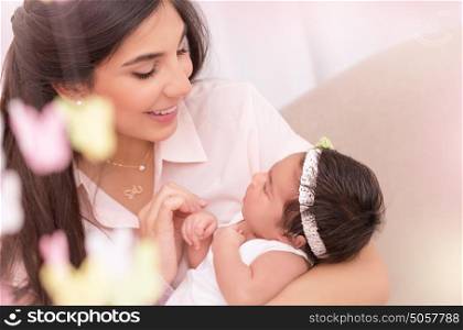 Portrait of beautiful young female holding on hands cute newborn daughter, enjoying motherhood, soft focus, happy family concept