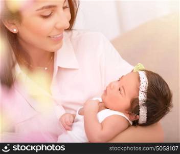 Portrait of beautiful young female holding on hands cute newborn daughter, enjoying motherhood, soft focus, happy family concept
