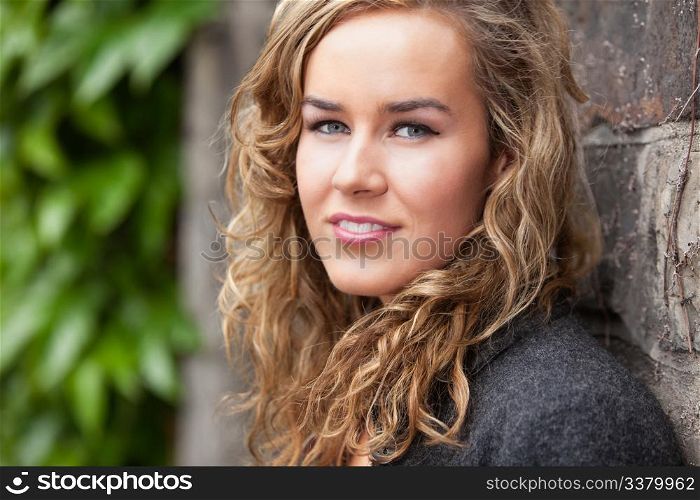 Portrait of beautiful young female leaning against stone wall