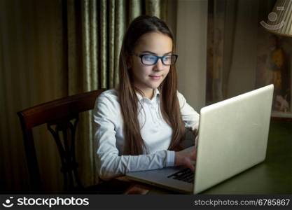Portrait of beautiful young girl using laptop at late evening