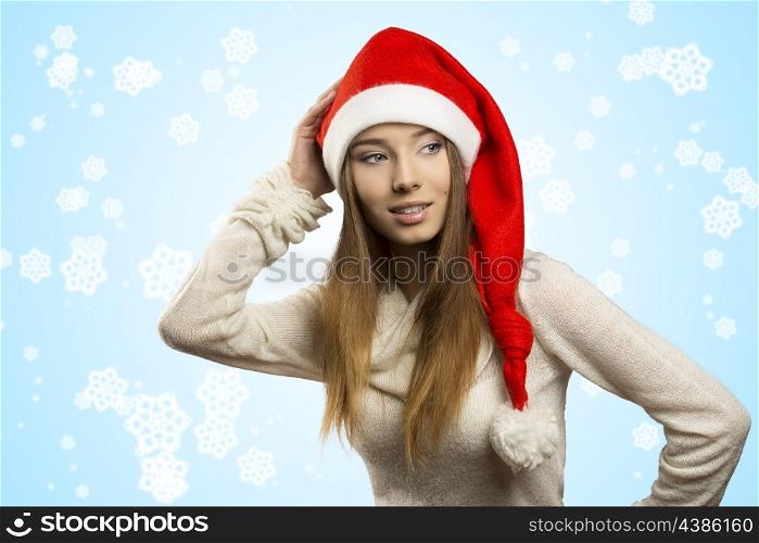 portrait of beautiful young girl with funny red christmas hat . She posing with long smooth hair, warm sweater and smiling &#xA;