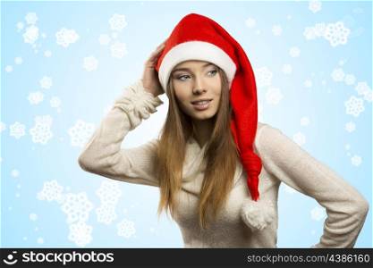 portrait of beautiful young girl with funny red christmas hat . She posing with long smooth hair, warm sweater and smiling &#xA;