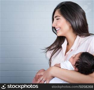 Portrait of beautiful young happy mother having fun with her little newborn baby at home, enjoying first day of motherhood, love and happiness concept