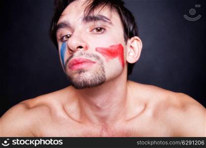 Portrait of beautiful young man with paint on his face lying on white pillow