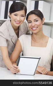 Portrait of beautiful young mixed race Hispanic woman or businesswoman in office meeting with Chinese Asian female colleague using a tablet computer