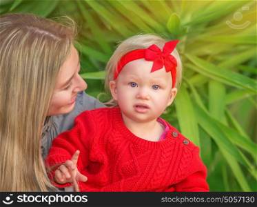 Portrait of beautiful young mother having fun in the park with her cute stylish little daughter, happy family enjoying spring time