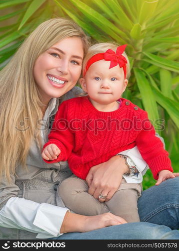 Portrait of beautiful young mother having fun in the park with her cute stylish little daughter, happy family enjoying spring time