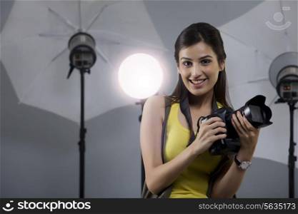 Portrait of beautiful young photographer holding camera in her studio