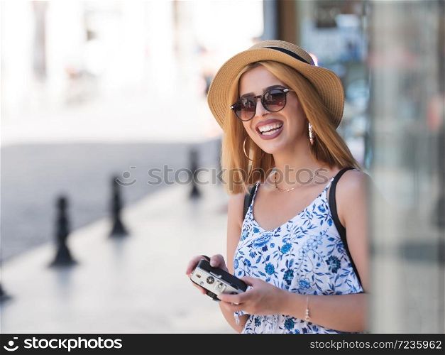 Portrait of beautiful young tourist girl in fashionable clothes with vintage retro camera during summer holiday vacation travel .Traveler Concept image. Beautiful girl explores streets of city with a retro camera
