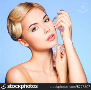 Portrait of beautiful young woman applies the ice to face on a blue background.