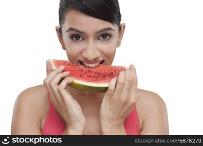 Portrait of beautiful young woman biting slice of watermelon over white background