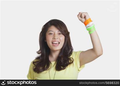Portrait of beautiful young woman cheering with clenched fist over white background