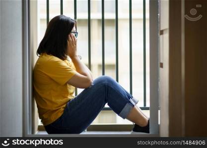 Portrait of beautiful young woman depressed woman sit on the floor near door at home. feeling sad tired and worried suffering depression. broken heart and Cyber bullying victim concept