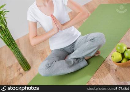 Portrait of beautiful young woman doing yoga exercise - Meditating with green apples and lucky bamboo