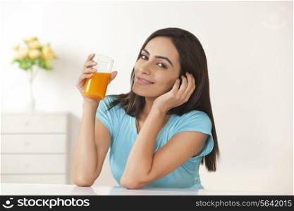 Portrait of beautiful young woman drinking orange juice at home