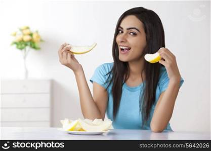 Portrait of beautiful young woman eating cantaloupe at home
