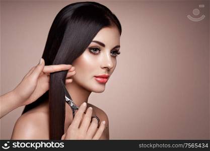 Portrait of beautiful young woman getting haircut. Brunette model. Hair salon, hairstylist. Care and beauty hair products. Perfect make-up