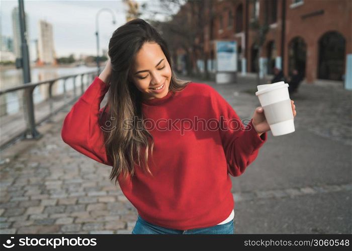 Portrait of beautiful young woman holding a cup of coffee outdoors. Urban concept.